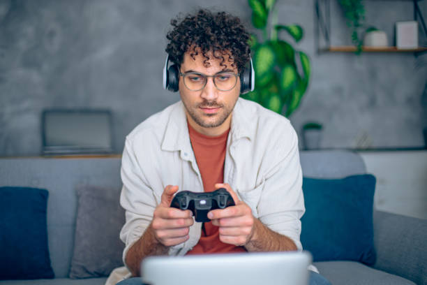 istock Young man is playing video game on digital tablet with headphones using hand controller 2186840225