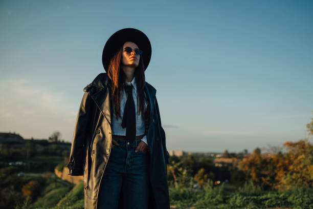 istock Stylish woman wearing hat and leather coat posing outdoors at sunset 2186840944