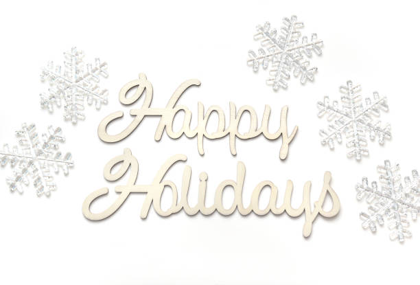 Closeup of mass produced snowflake ornaments and text reading Happy Holidays on a white background.
