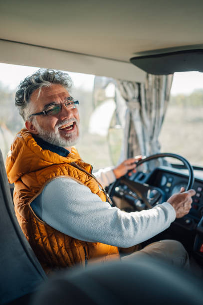 istock Happy senior bus driver holding steering wheel and smiling 2186847498
