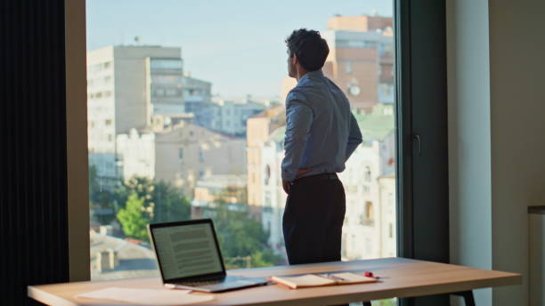 istock Serious businessman thinking project standing at office panoramic window. 2186847702