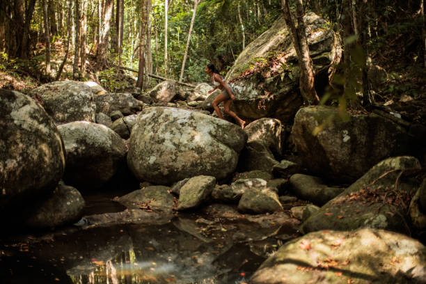 Thai woman adventurer Walking on a rock in the middle of a tropical rainforest, in Koh Phangan, Thailand.