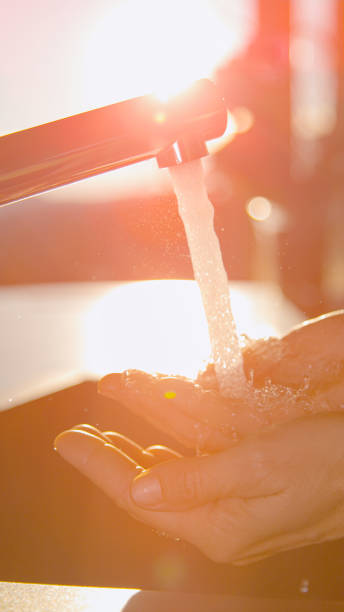 istock CLOSE UP Cupped hands under modern kitchen faucet with running fresh piped water 2186853137