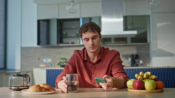 istock Disappointed guy receiving message smartphone drinking coffee home closeup. 2186853373