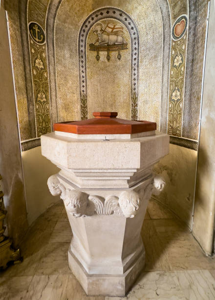 Trieste, Italy - June 27, 2024: Chiesa S. Antonio Vecchio, Church of St. Anthony the Elder. Baptismal font is a piece of art with heads of children sculpted on six corners