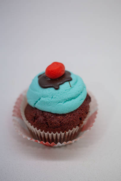 Red velvet muffin with bright blue sugar cream isolated on a white background close up
