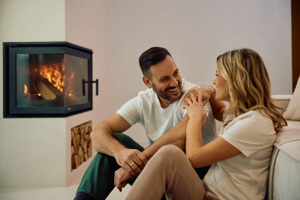 istock Happy man and his wife communicating while relaxing by fireplace at home. 2186856072