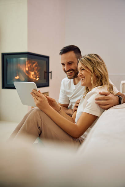 istock Happy couple surfing the net on touchpad while relaxing at home. 2186856080
