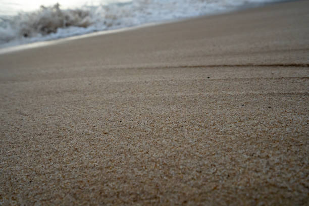 Wave crashing on sandy beach at sunset, overcast, Antibes, autumn