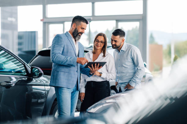 istock Interactive teamwork with tablet among cars in dealership. 2186859065