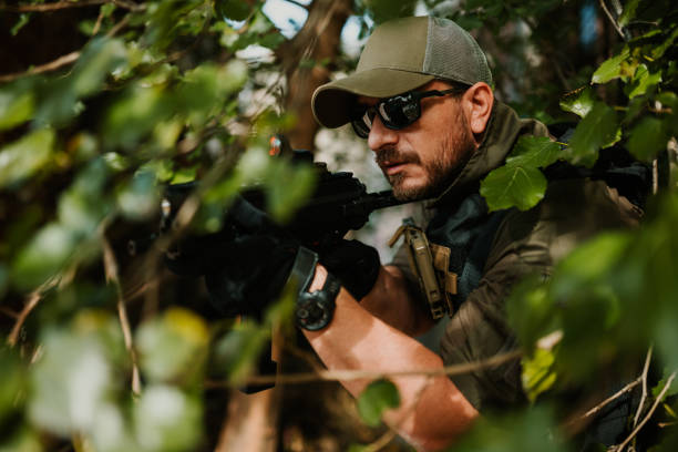 istock Soldier aiming with assault rifle in dense foliage 2186860717