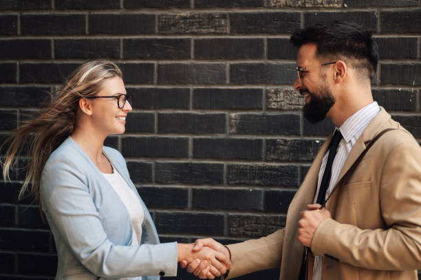 istock Businesspeople shaking hands in front of brick wall 2186861460