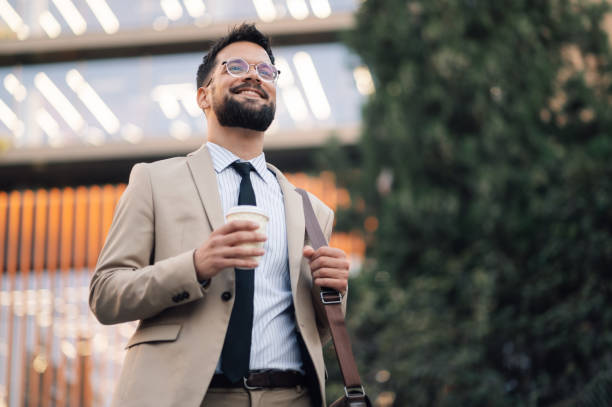 istock Smiling businessman walking with coffee and bag in urban setting 2186861490