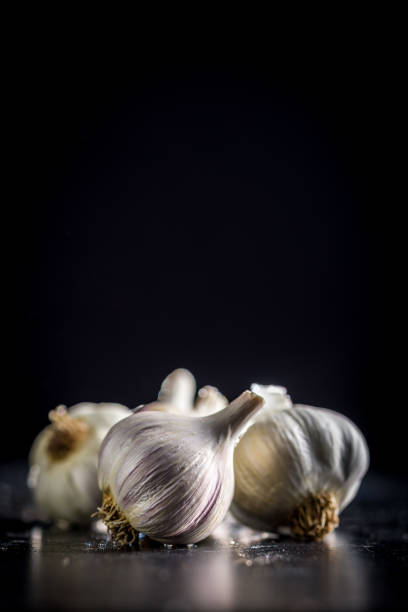 Unpeeled garlic bulbs cloves on a black table.