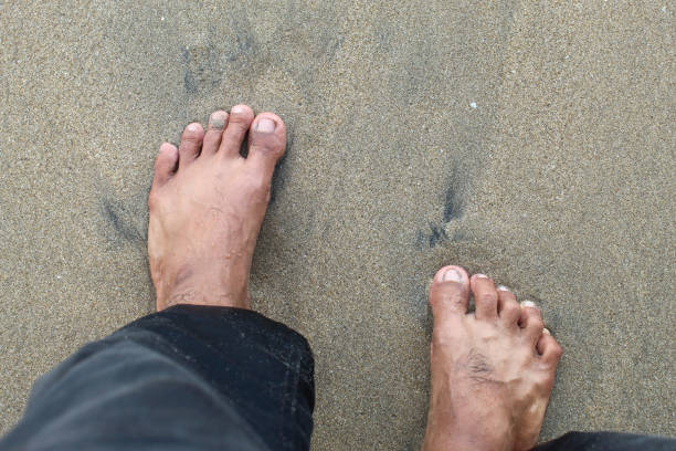 istock Man's feet standing on the beach sand 2186862311