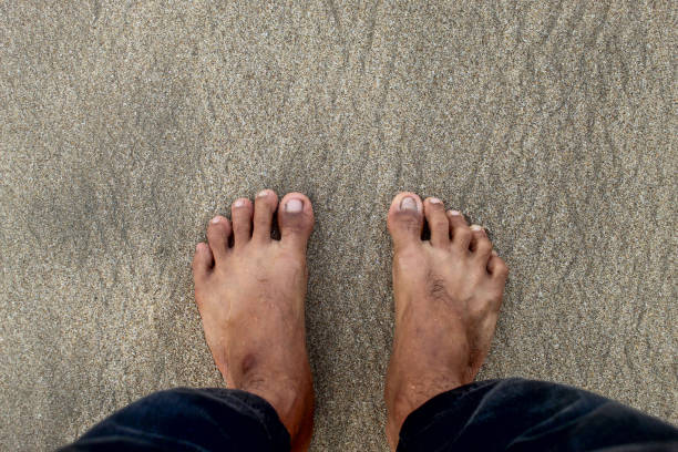 istock Man's feet standing on the beach sand 2186862853