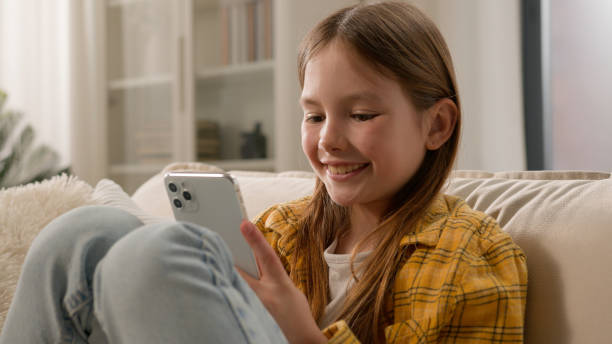 istock Smiling happy kid girl sending message checking email using mobile phone cute schoolgirl child chatting with friends on social network internet playing online game watching video on smartphone at home 2186863794