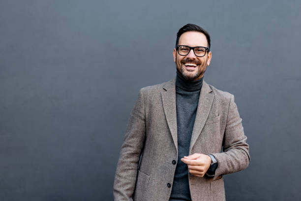 istock Laughing man in grey turtleneck and blazer on grey background. 2186864037
