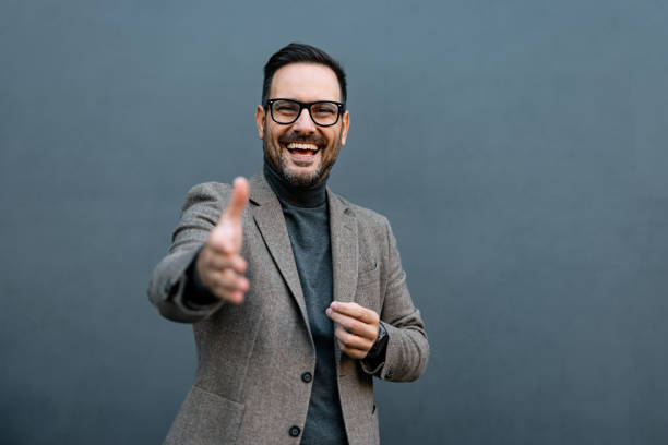 istock Laughing man extends hand for a handshake on gray background. 2186864101