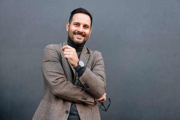 istock Smiling man in blazer and turtleneck, holding eyeglasses. 2186864644
