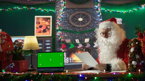 istock Father Christmas reading letters from children next to green screen display 2186864893