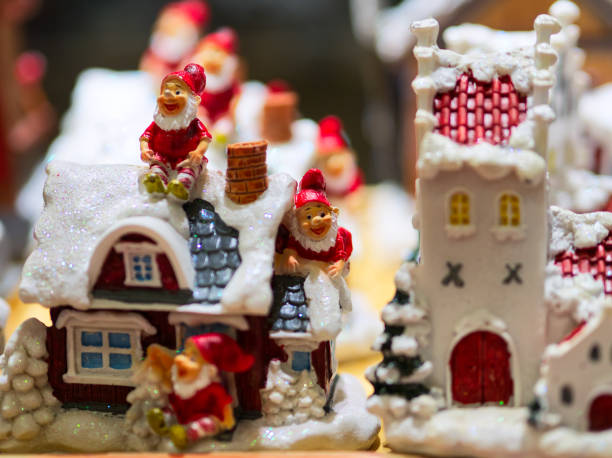 Decorative holiday gnomes surrounded by festive ornaments and white garland, placed in front of a beautiful bokeh Christmas tree, creating a charming and cozy seasonal atmosphere.
