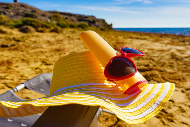A beach scene with a yellow hat on top of a beach chair. Summer holidays on the coast
