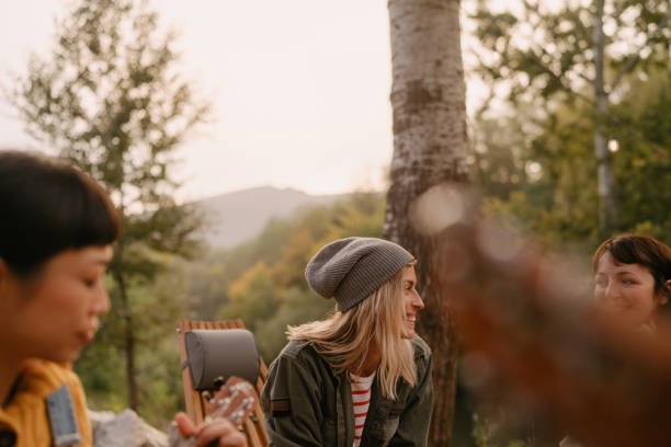 Photo of friends enjoying their escape from the city noise, playing music outdoors at sunset, surrounded by serene nature