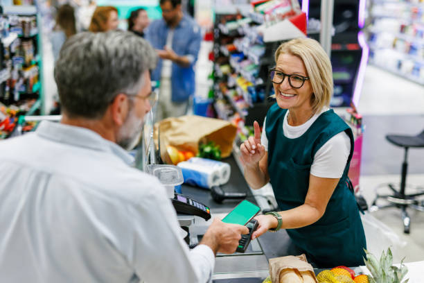 istock Customer paying with smartphone at grocery store checkout: cashier assisting 2186871931