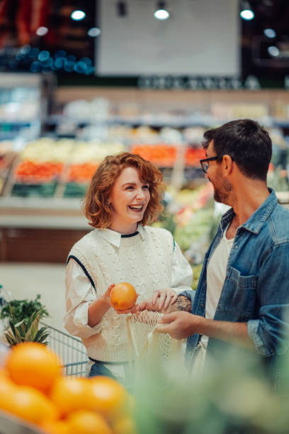 istock Cheerful couple choosing oranges at the supermarket 2186872007