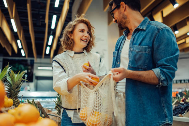 istock Young couple buying fresh oranges at grocery store using reusable bag 2186872011