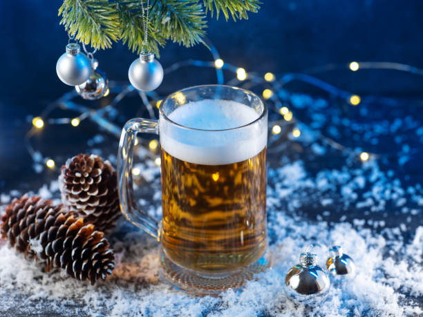istock Christmas light beer mug on a snowy table. Christmas tree branch with balls and cones 2186872264