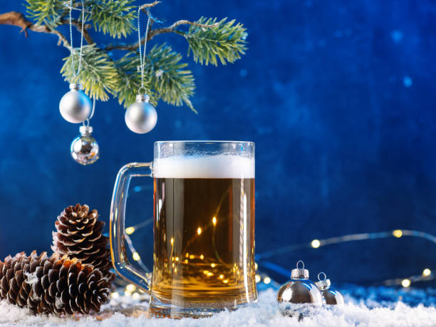 istock Christmas light beer mug on a snowy table. Christmas tree branch with balls and cones. Copy space 2186872266