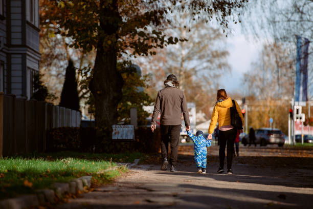 istock A loving couple strolls through a sunlit park with their young son, surrounded by the vibrant colors of autumn, enjoying a joyful and peaceful family moment together. 2186874029