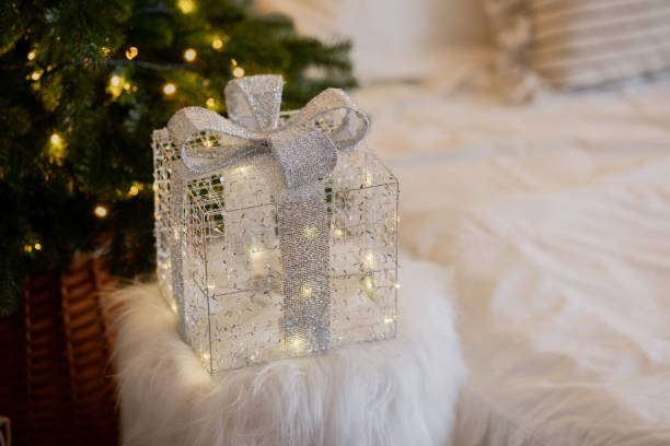 istock Decorative Christmas gift box with lights placed in a cozy room setting 2186876892