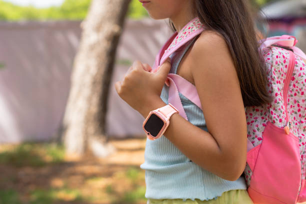 istock Elementary age girl wearing smartwatch and carrying backpack at park 2186878187