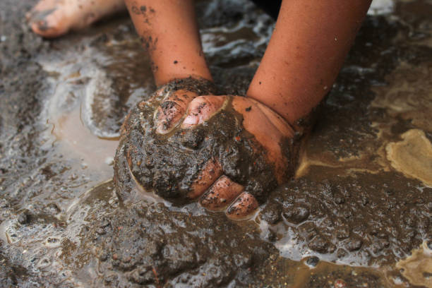 istock Little child's hands playing with wet sand and mud.  Child playing outdoors in wet mud 2186879863
