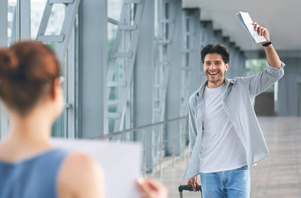 Passenger walking with luggage to woman with name board