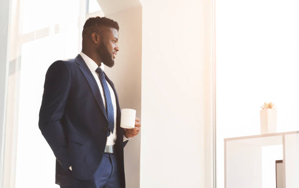 istock Handsome african businessman drinking coffee near window in office 2186889261
