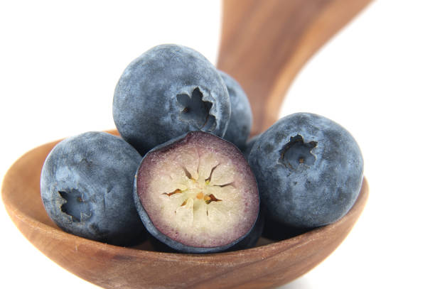 Close-up of ripe blueberries in a wooden spoon, highlighting their vibrant color and juicy texture. Perfect for emphasizing health benefits and nutrition in culinary or dietary contexts.