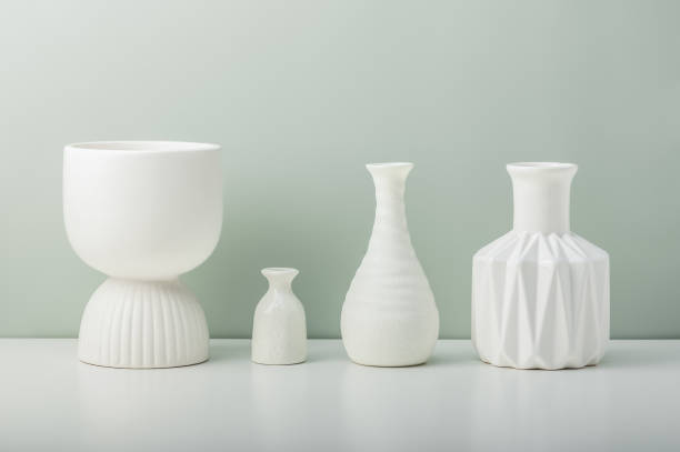 istock Four white ceramic vases on a white table against an olive wall. 2186909704