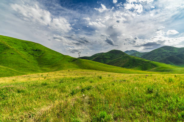istock Dramatic cloudy sky over green hills and green flowering meadow. 2186909783