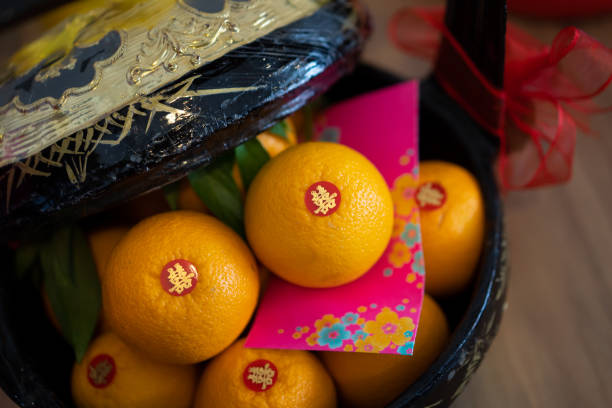 Fresh mandarin oranges with 'Double Happiness' calligraphy stickers, stacked elegantly in a wooden basket. Chinese wedding concept. Celebrations and blessings concept.