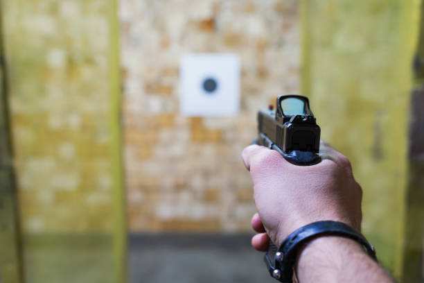 istock Shooting a modern pistol with a red dot sight at a paper target at an indoor shooting range. 2186910941