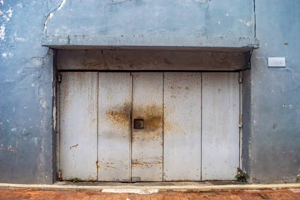 istock An old, weathered garage door with rust stains and peeling paint on a blue wall background, showcasing urban decay and vintage charm 2186919296