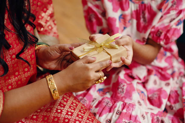 istock Exchanging Gift Wrapped In Gold Ribbon Between Two People 2186921718