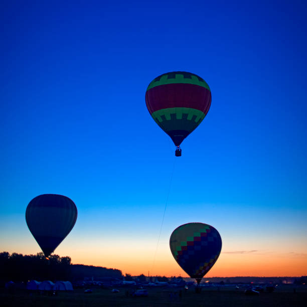 istock Three Prodigious Colorful Air Balloons Levitating Over the Ground Outdoors Against Clear Blue Skies At Twilight. 2186923243