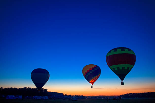 istock Three Prodigious Colorful Air Balloons Levitating Over the Ground Outdoors Against Clear Blue Skies At Twilight. 2186923480
