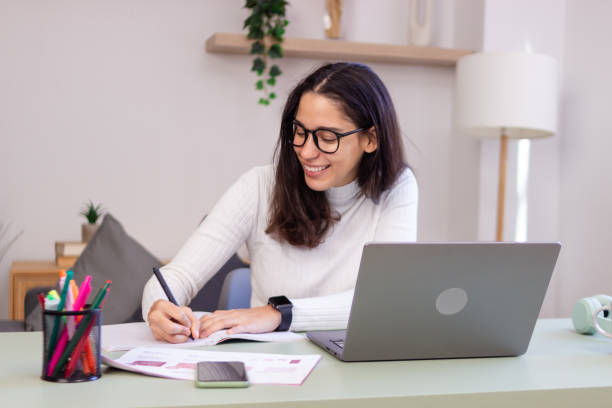 istock Young woman working from home taking notes and smiling 2186927675
