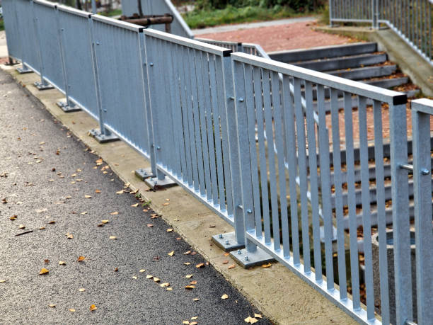 istock bridge railing with vertical fence posts anchored into the ground with four concrete screws. the railing is fixed from the side of the bridge into the concrete. 2186928978